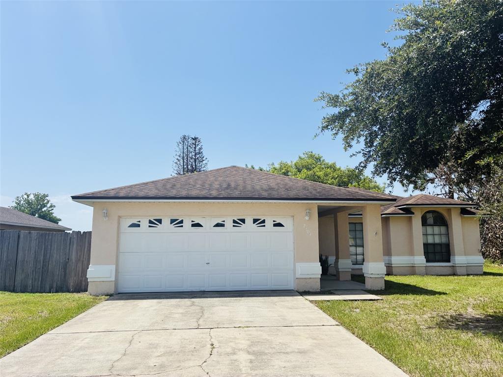 A single-story house with a beige stucco exterior, a two-car garage, and a concrete driveway — 2704 KENDALL AVENUE, KISSIMMEE, FL