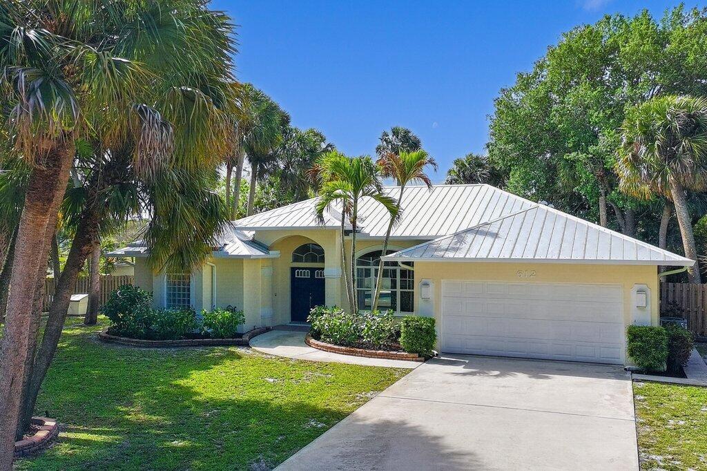 A single-story yellow house with a white metal roof and a two-car garage — 612 SE 6th Street, Stuart FL 34994, STUART, FL