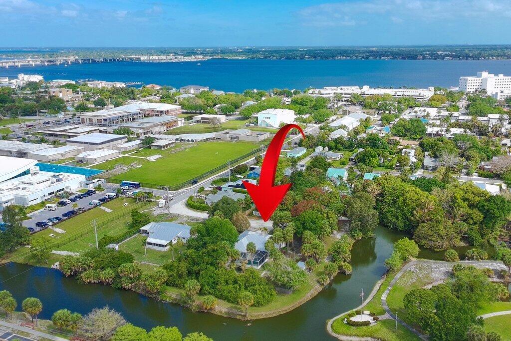 An aerial view shows a house with a screened pool enclosure situated near a canal — 612 SE 6th Street, Stuart FL 34994, STUART, FL
