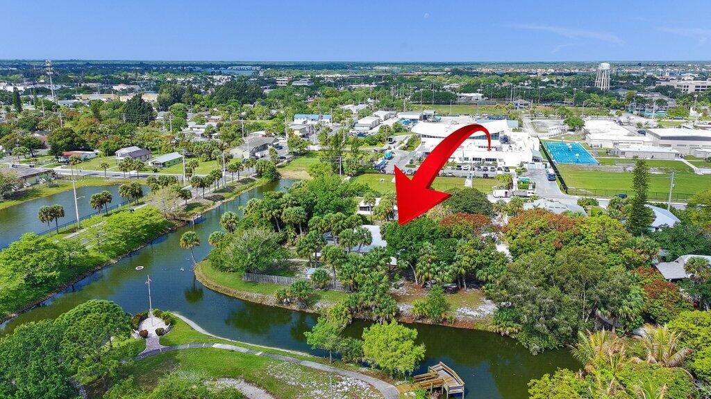 An aerial view shows a house surrounded by trees and a canal near a school — 612 SE 6th Street, Stuart FL 34994, STUART, FL