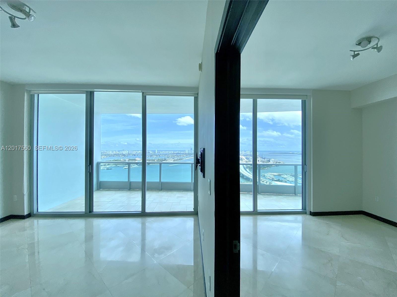 Two adjacent rooms with marble floors and floor-to-ceiling windows overlooking a bay and bridge — 900 Biscayne Blvd # 3803, Miami FL 33132, MIAMI, FL