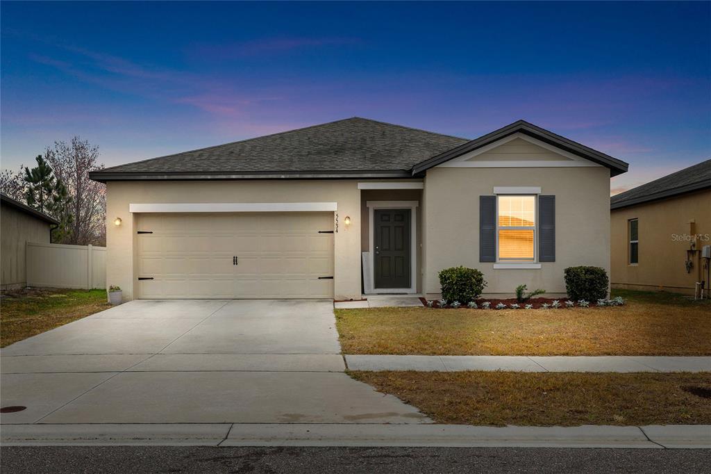 A single-story suburban house with a two-car garage, tan stucco exterior, and a front lawn — 5534 TURKEY CREEK WAY, LAKELAND, FL