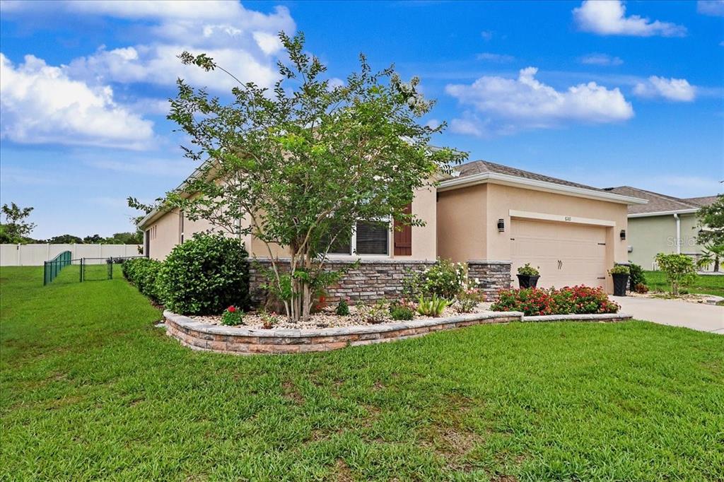 A single-story house with a tan stucco exterior, stone accents, and a front-facing garage — 6265 SW 88 LOOP, OCALA, FL