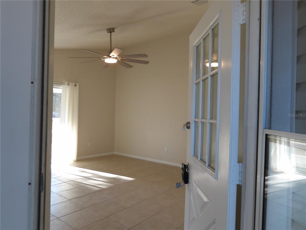 A view through an open door into a tiled living room with a ceiling fan — 75 WELLWOOD LANE UNIT A, PALM COAST, FL