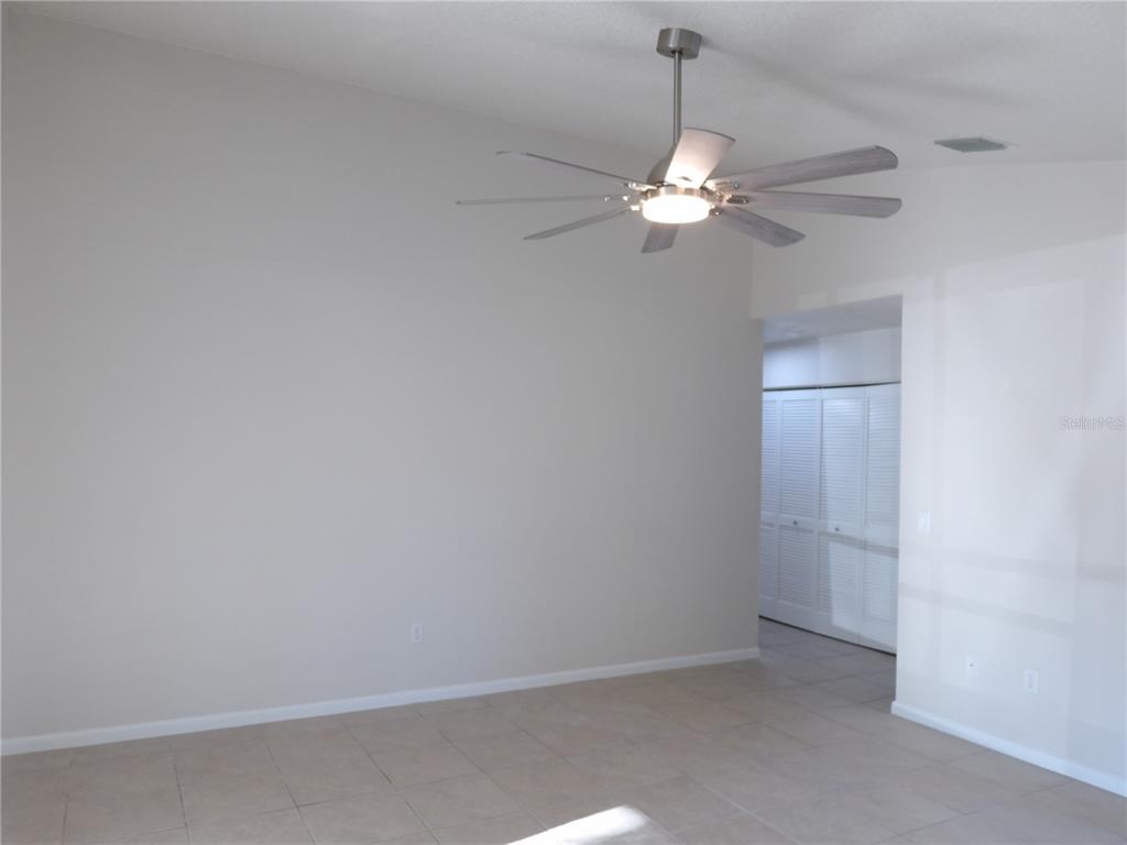 A spacious room features light-colored tile flooring, a vaulted ceiling, and a modern ceiling fan — 75 WELLWOOD LANE UNIT A, PALM COAST, FL