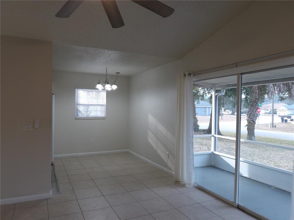 A dining area features tile flooring, a chandelier, and sliding glass doors to a porch — 75 WELLWOOD LANE UNIT A, PALM COAST, FL