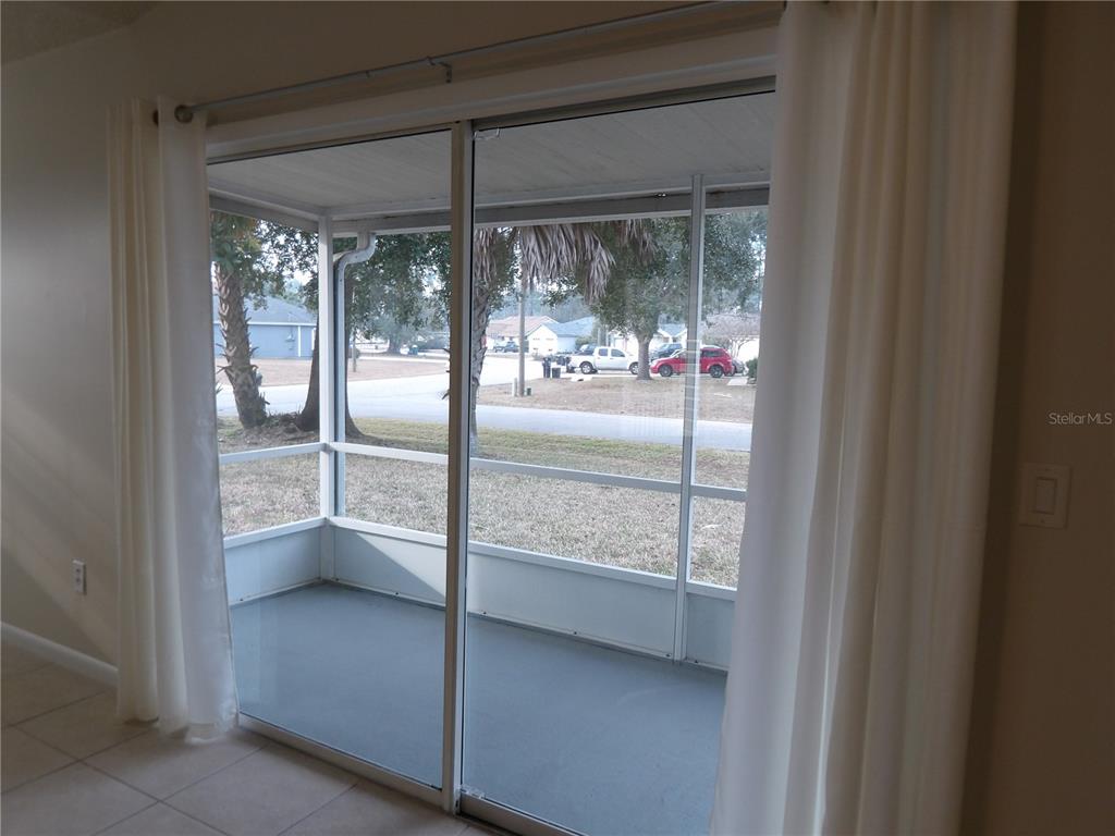 A sliding glass door opens to a screened-in porch with a gray floor — 75 WELLWOOD LANE UNIT A, PALM COAST, FL