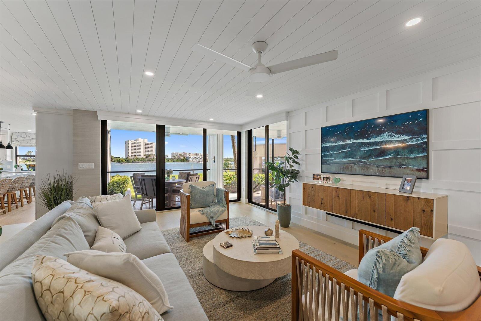 A bright living room features a white paneled wall, floating wood console, and waterfront views — 19800 Sandpointe Bay Drive # 101, Tequesta FL 33469, TEQUESTA, FL