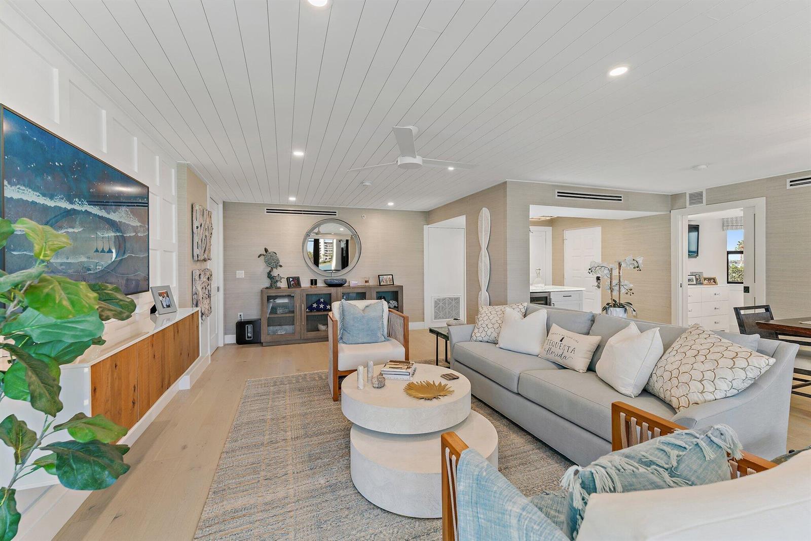A bright living room features light wood floors, a white paneled ceiling, and coastal decor — 19800 Sandpointe Bay Drive # 101, Tequesta FL 33469, TEQUESTA, FL