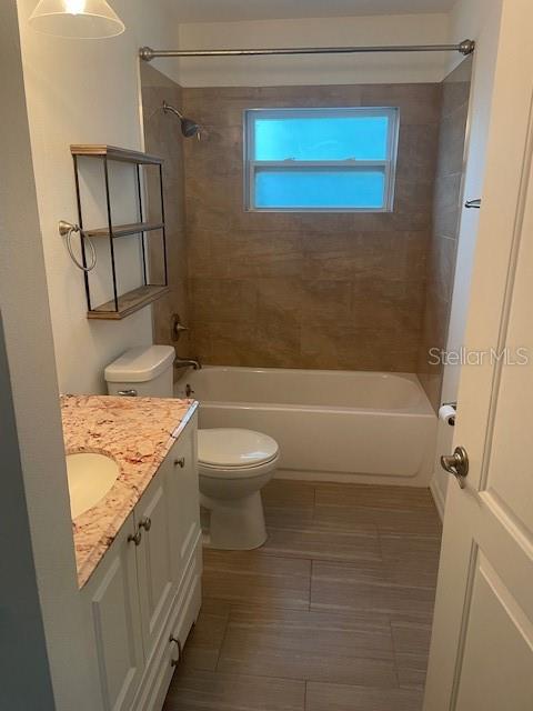 A bathroom features a vanity with a stone countertop, a toilet, and a tiled tub-shower — 1610 HAVEN DRIVE UNIT Rear, ORLANDO, FL