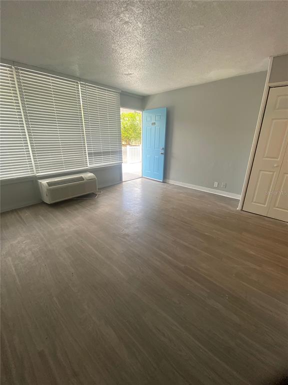An empty room features light-colored wood-look flooring, a window with blinds, and a blue door — 515 BON AIR STREET UNIT 146, LAKELAND, FL