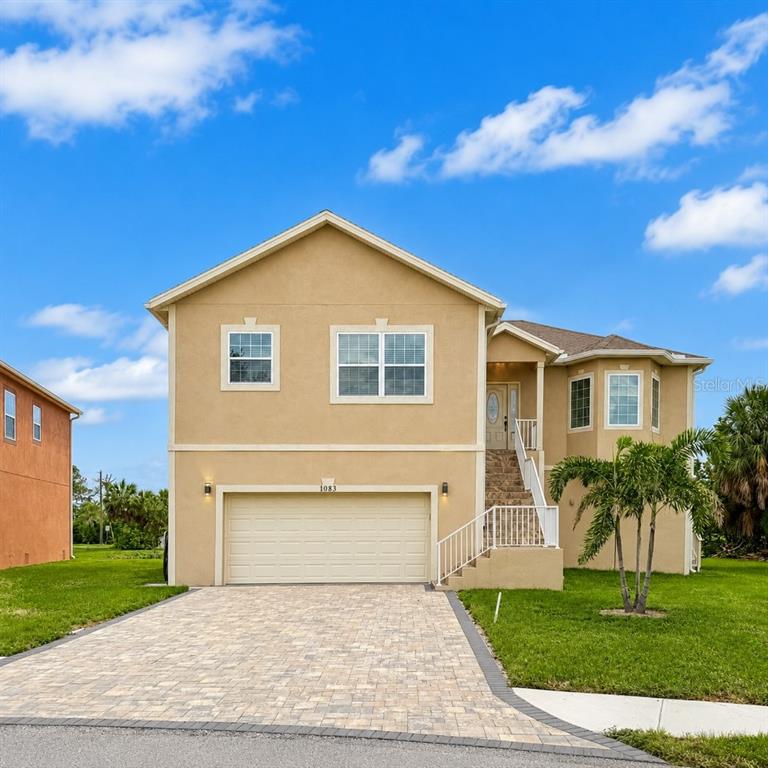 A two-story tan house with a two-car garage and a paved driveway — 1083 S POINTE ALEXIS DRIVE, TARPON SPRINGS, FL