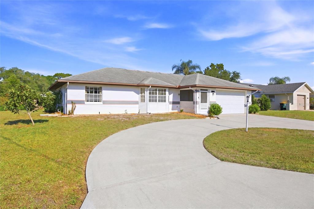 A single-story house with a white exterior, a gray roof, and a curved concrete driveway — 4201 LOQUAT ROAD, SEBRING, FL