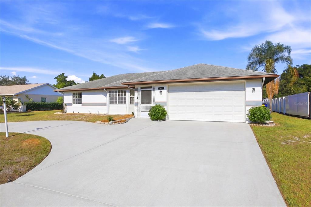 A single-story house with a white exterior, a gray roof, and a curved concrete driveway — 4201 LOQUAT ROAD, SEBRING, FL