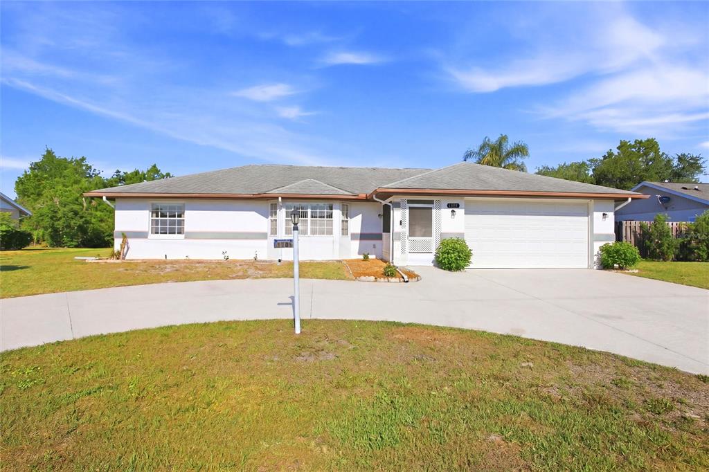 A single-story house with a white exterior, a two-car garage, and a concrete driveway — 4201 LOQUAT ROAD, SEBRING, FL