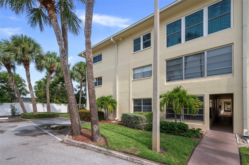 An exterior view of a three-story apartment building with palm trees and a parking lot — 4780 COVE CIRCLE STREET UNIT 103, ST PETERSBURG, FL