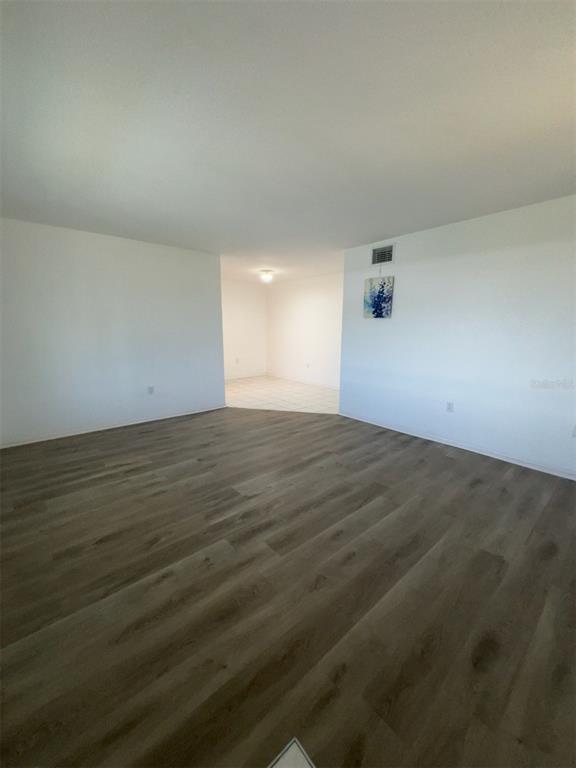 A spacious room with light-colored walls and wood-look flooring leads to a tiled area — 1700 6TH STREET NW UNIT A38, WINTER HAVEN, FL