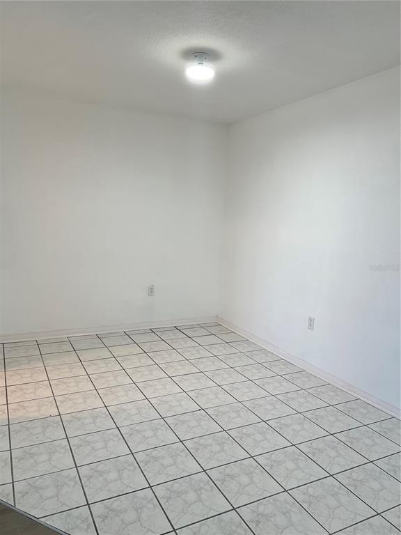 An empty room with white walls, a ceiling light fixture, and light-colored tiled flooring — 1700 6TH STREET NW UNIT A38, WINTER HAVEN, FL