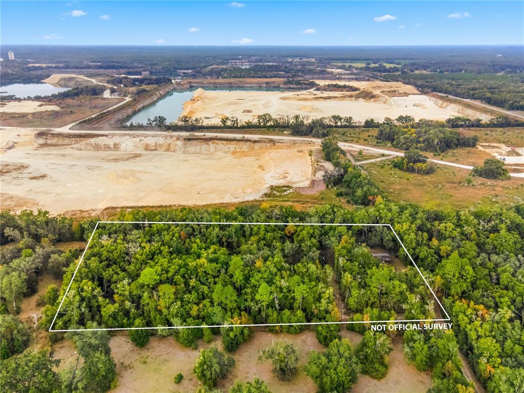 An aerial view shows a rectangular wooded lot outlined in white near a large quarry — 20614 NW 10TH PLACE, NEWBERRY, FL