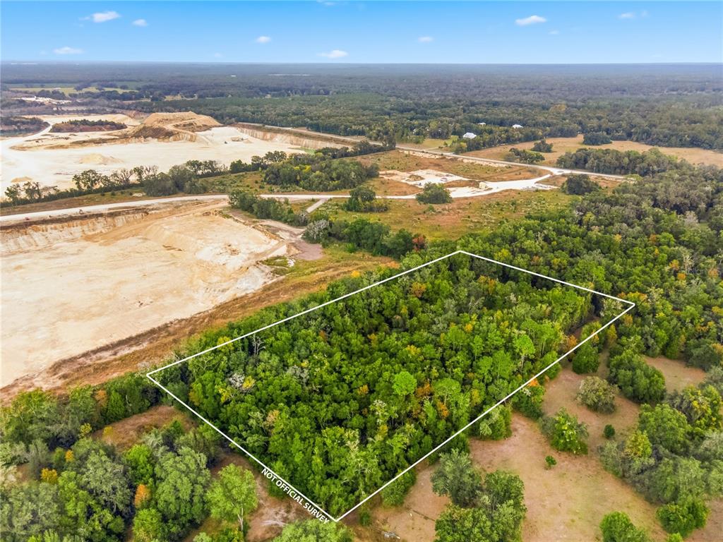 An aerial view shows a rectangular plot of wooded land adjacent to a large quarry — 20614 NW 10TH PLACE, NEWBERRY, FL
