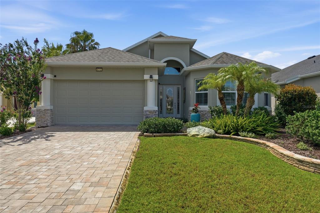 A single-story house with a beige stucco exterior, a paved driveway, and a landscaped front yard — 8732 PROVIDENCE COURT, MOUNT DORA, FL