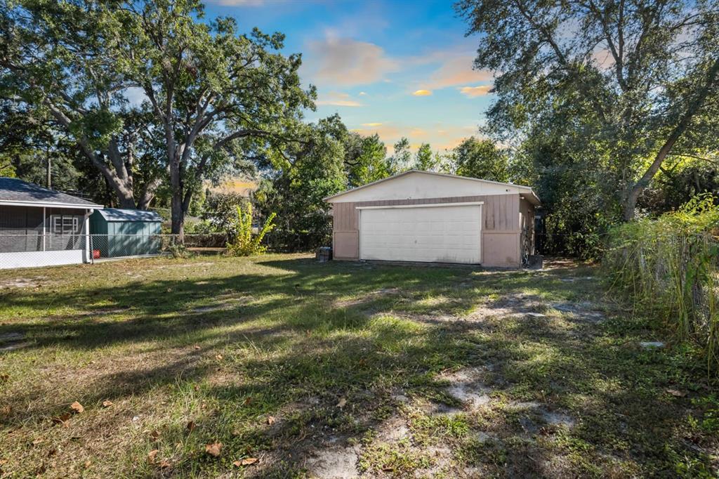 A detached garage sits in a grassy backyard next to a small shed and trees — 1217 LAMBRIGHT STREET, TAMPA, FL