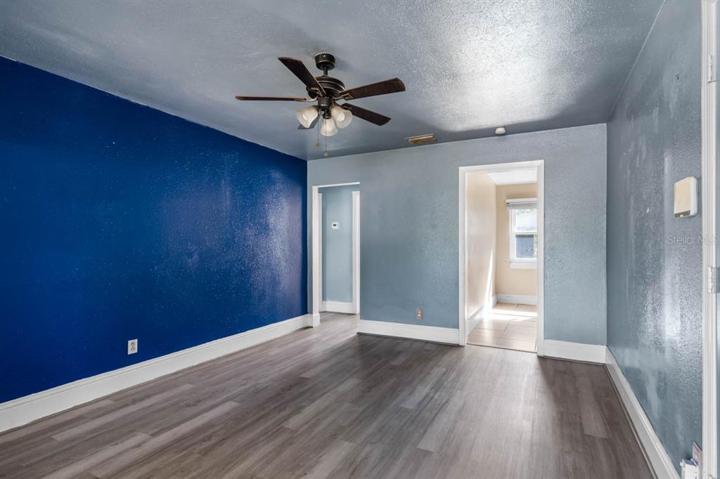 A room with gray wood-look flooring, a blue accent wall, and a ceiling fan — 1217 LAMBRIGHT STREET, TAMPA, FL