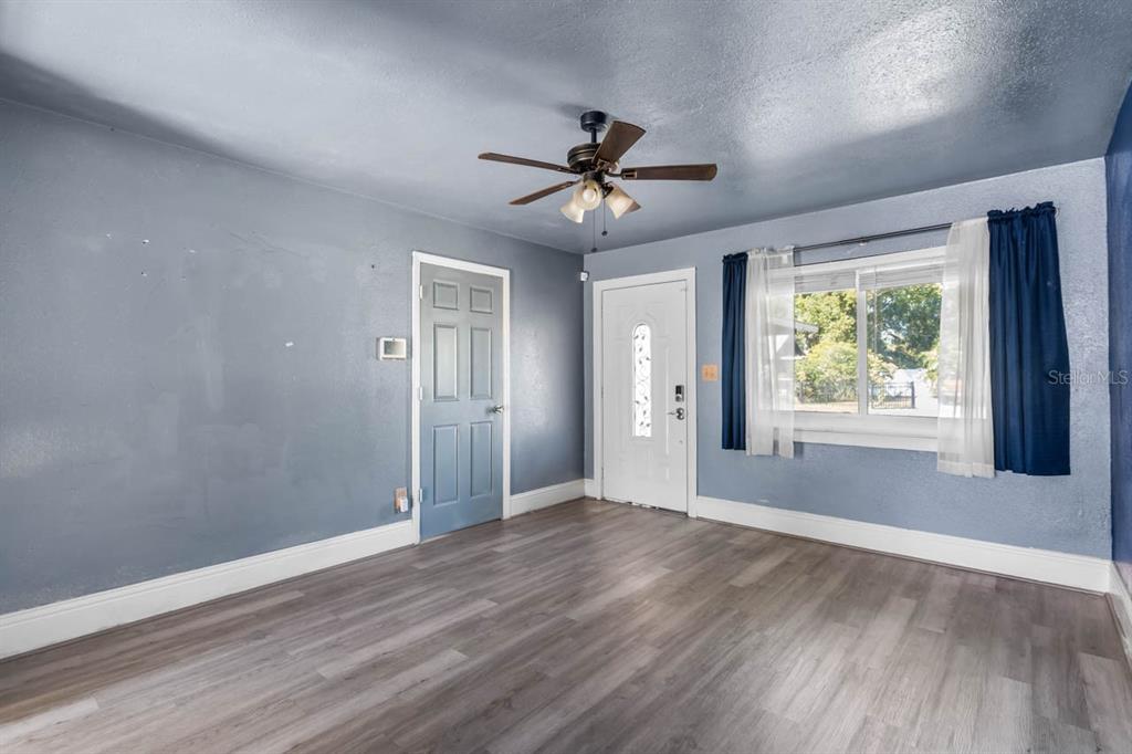 A room with blue walls, wood-look flooring, a ceiling fan, and two doors — 1217 LAMBRIGHT STREET, TAMPA, FL