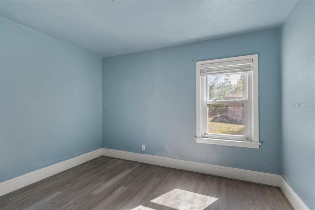A bedroom with light blue walls, gray wood-look flooring, and a single window — 1217 LAMBRIGHT STREET, TAMPA, FL