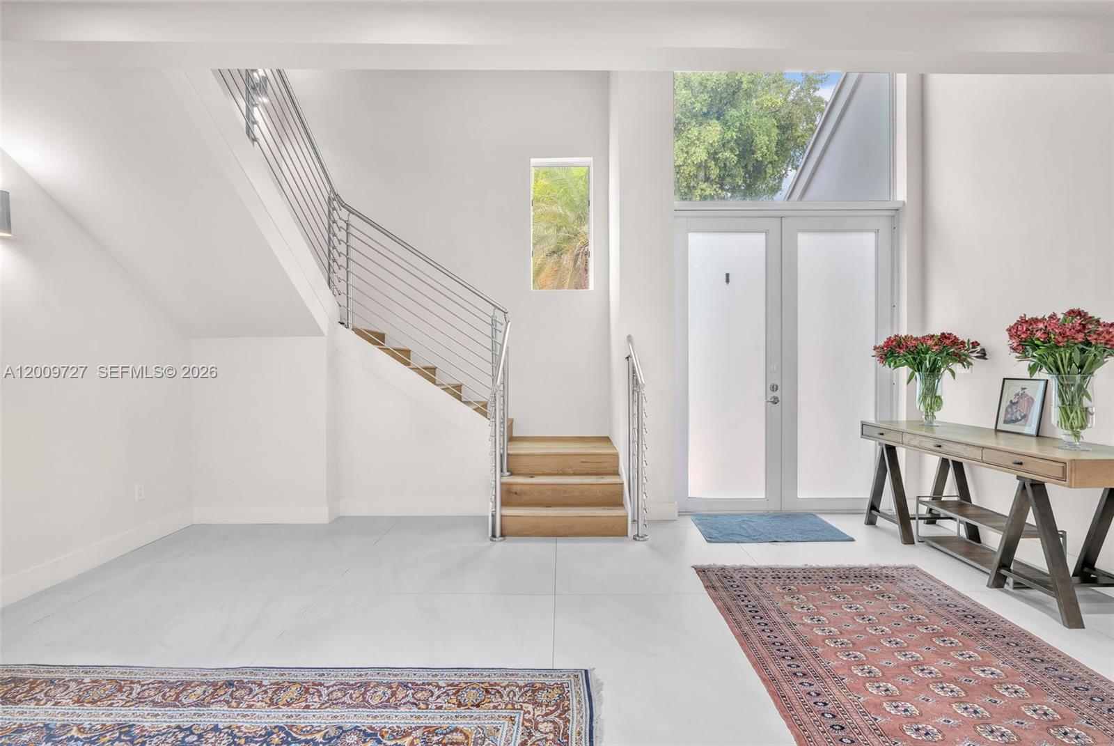 A bright entryway features white tile floors, a wooden staircase with metal railings, and double doors — 1933 S Oak Haven Cir, Miami FL 33179, MIAMI, FL