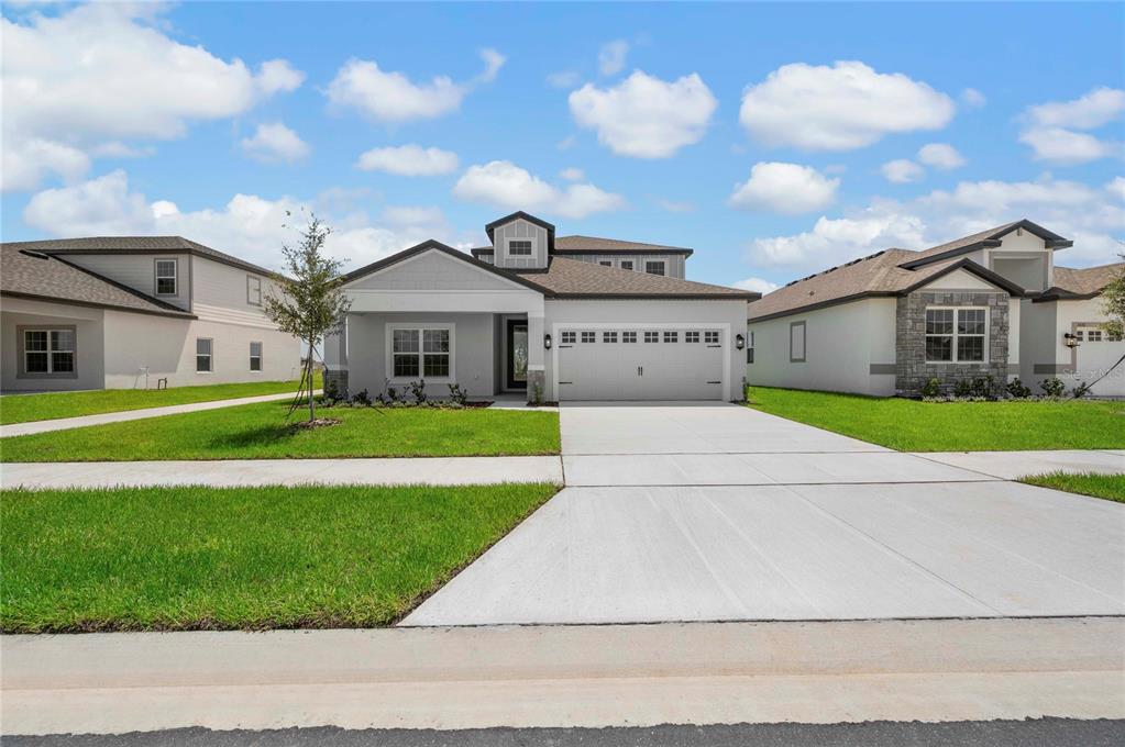 A single-story suburban house with a gray exterior, two-car garage, and a front lawn — 3384 CHINOTTO DRIVE, LAKE ALFRED, FL