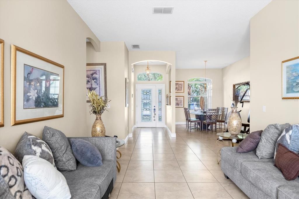 A living room with tile floors leads to a dining area and a front entryway — 100 HOLLYBROOK COURT, DAVENPORT, FL