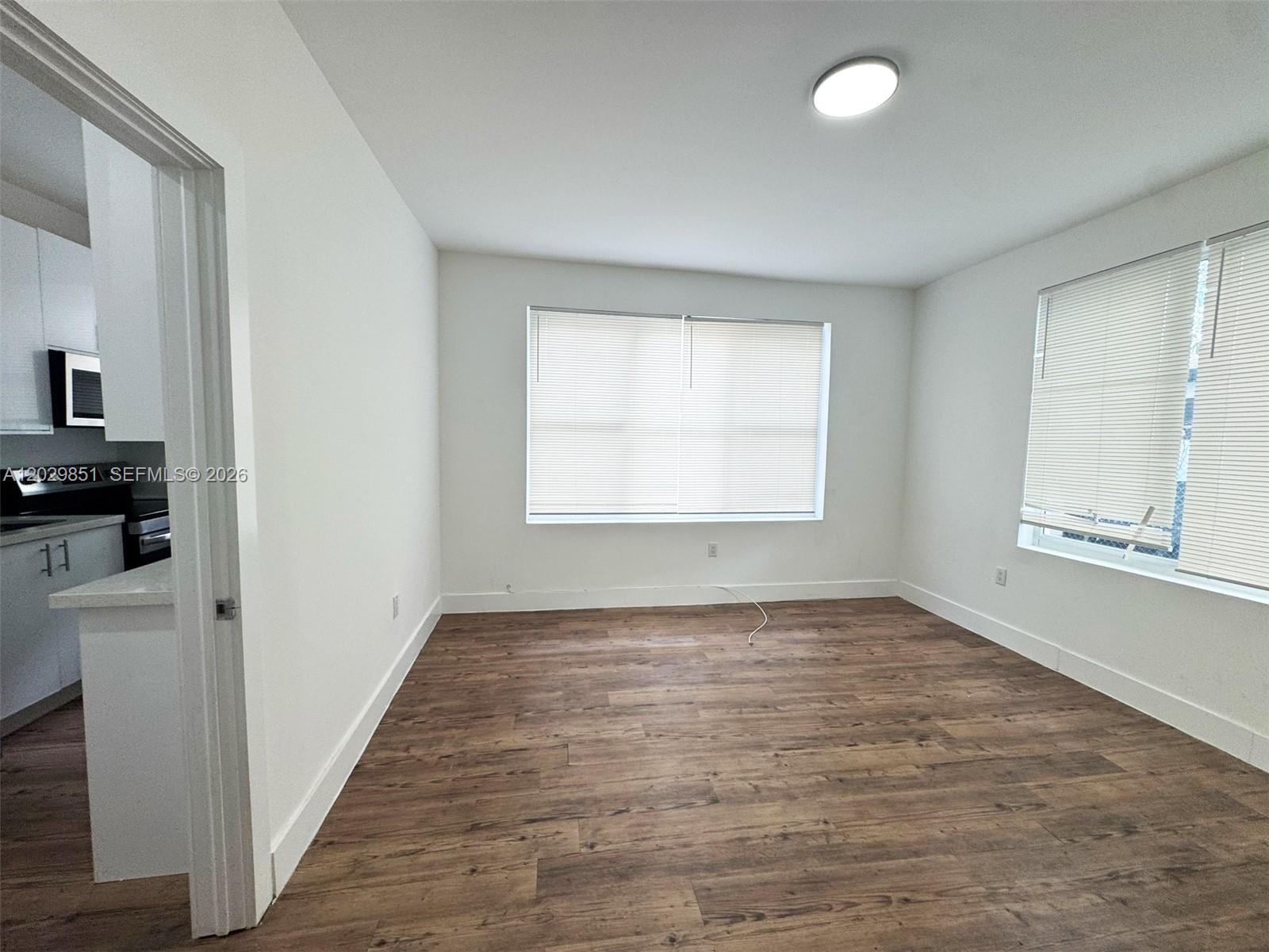 An empty room features white walls, wood-look flooring, and two windows with blinds — 321 SW 9th Ave # 4, Miami FL 33130, MIAMI, FL