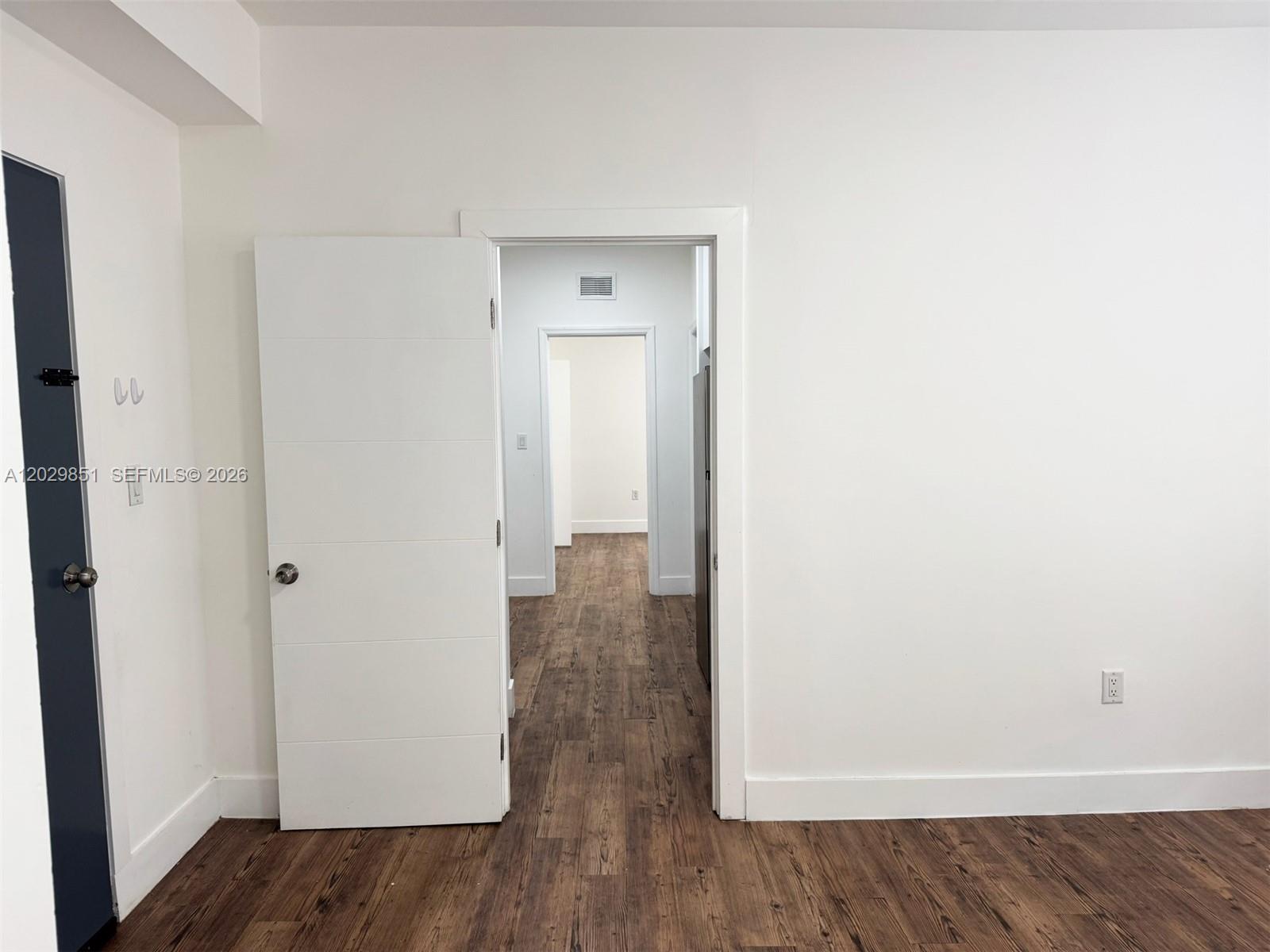 A white-walled room with wood-look flooring features an open doorway leading to another room — 321 SW 9th Ave # 4, Miami FL 33130, MIAMI, FL