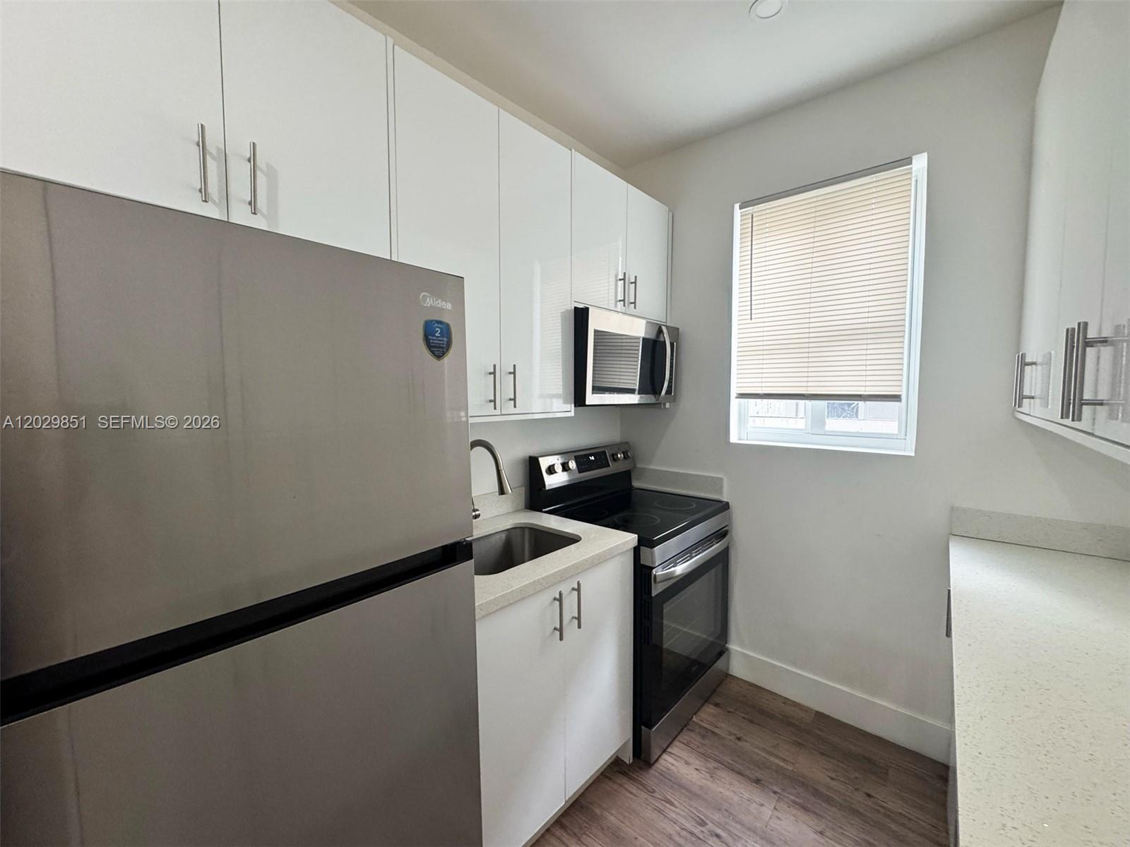 A compact kitchen features white cabinets, stainless steel appliances, and light-colored countertops — 321 SW 9th Ave # 4, Miami FL 33130, MIAMI, FL