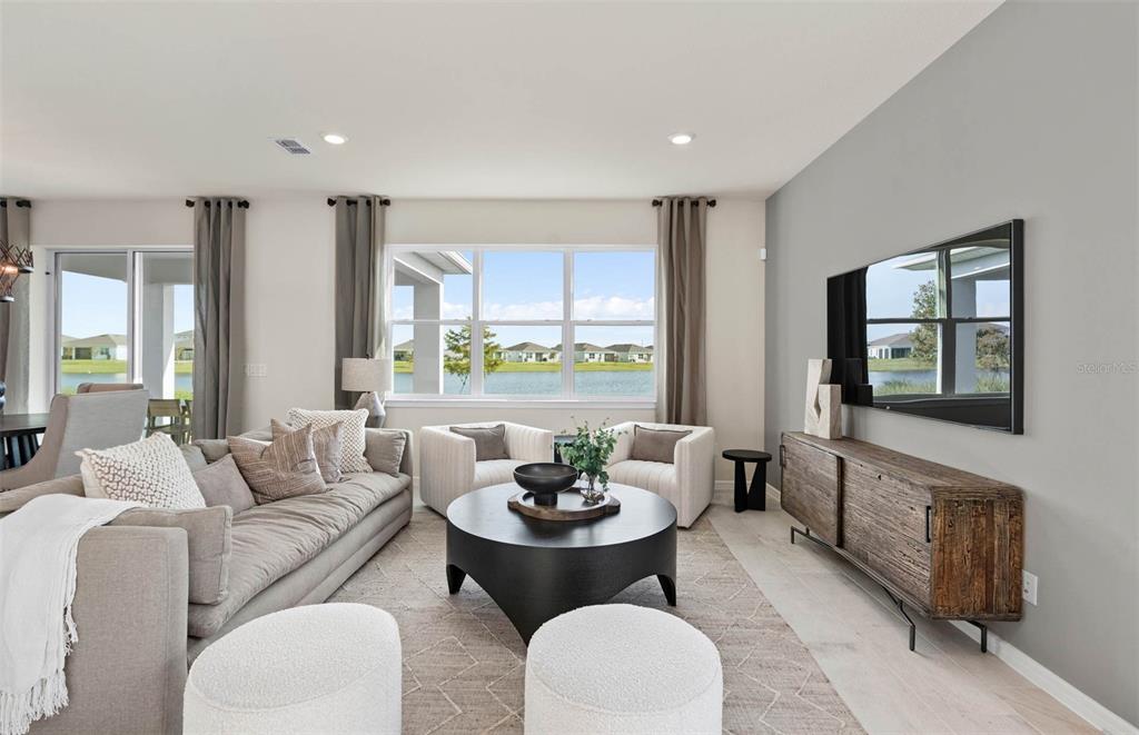 A living room features a grey accent wall, a television, and a view of water — 5262 CURRANT STREET, LAKELAND, FL