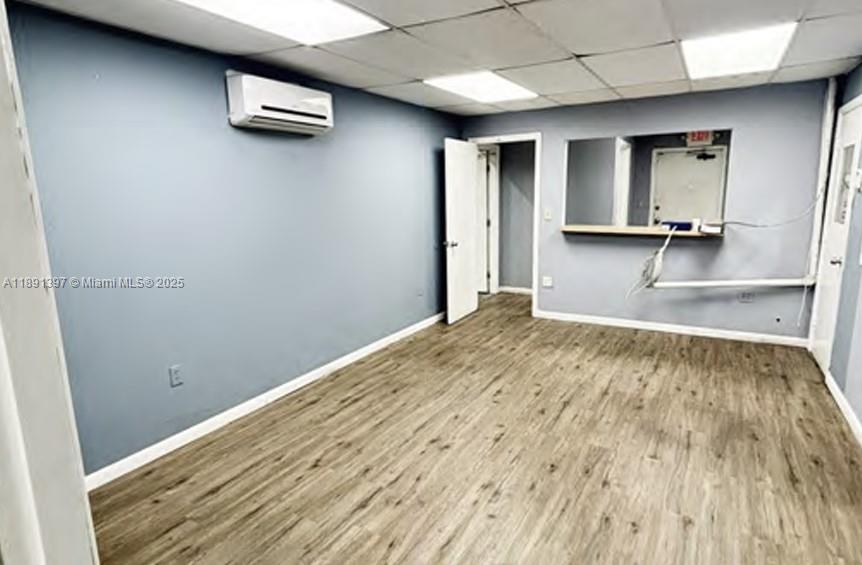 An empty room with light blue walls, wood-look flooring, a wall-mounted air conditioner, and doors — 4201 NW 37th Ct # 4239, Hialeah FL 33142, HIALEAH, FL