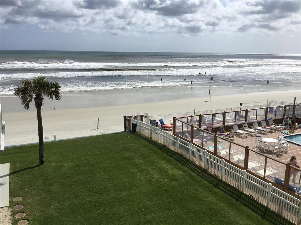 An elevated view of a grassy lawn, a pool deck, and a sandy beach — 1571 S ATLANTIC AVENUE UNIT 308, NEW SMYRNA BEACH, FL