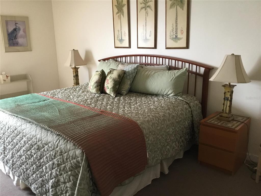 A bedroom features a bed with a wooden headboard, patterned bedding, and two bedside lamps — 1571 S ATLANTIC AVENUE UNIT 308, NEW SMYRNA BEACH, FL