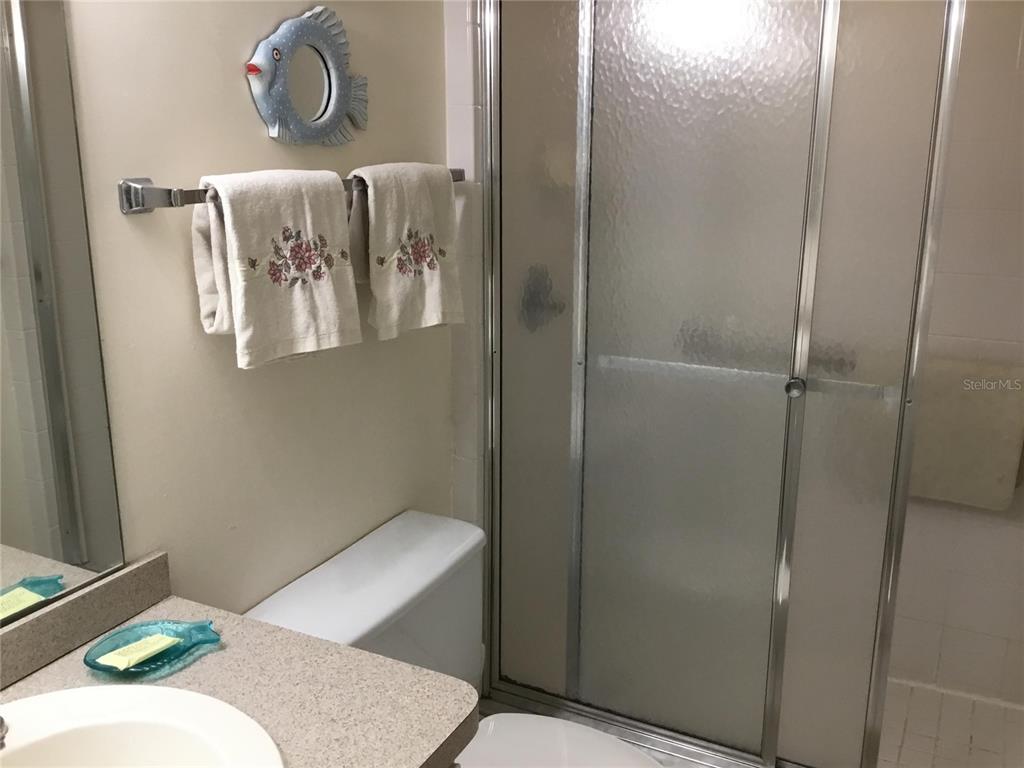 A bathroom features a vanity, a toilet, and a glass-enclosed shower with tiled walls — 1571 S ATLANTIC AVENUE UNIT 308, NEW SMYRNA BEACH, FL