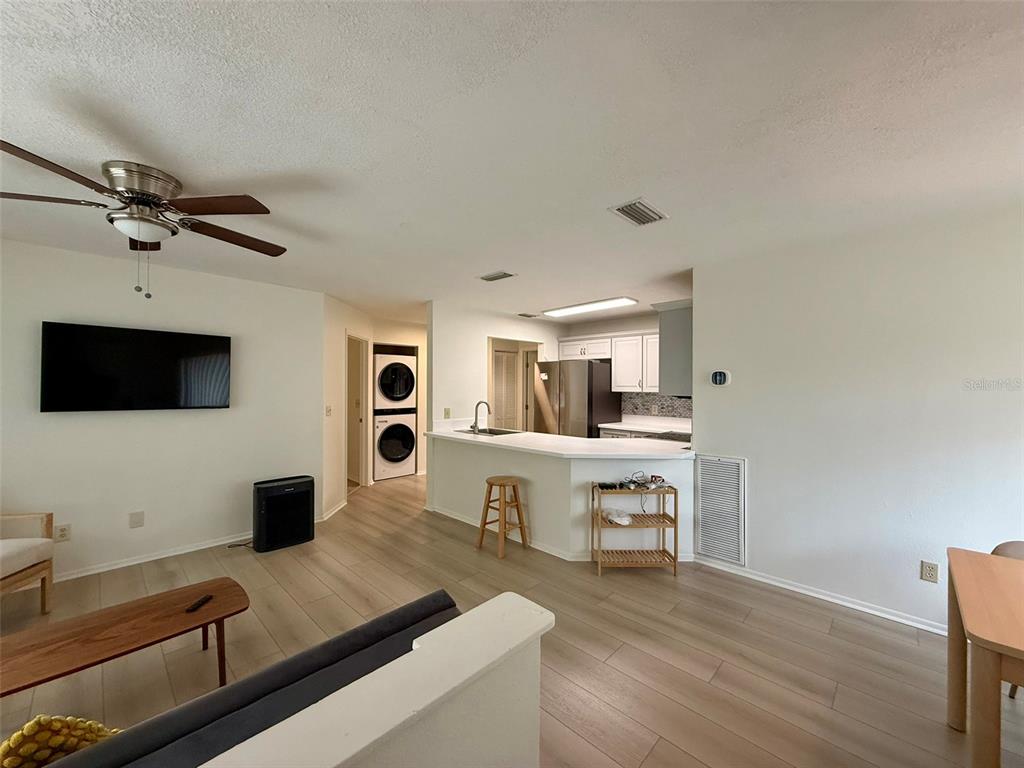 An open-concept living area features light wood flooring, a kitchen with white cabinets, and laundry — 5202 WATERVIEW WAY UNIT 5202, WINTER HAVEN, FL