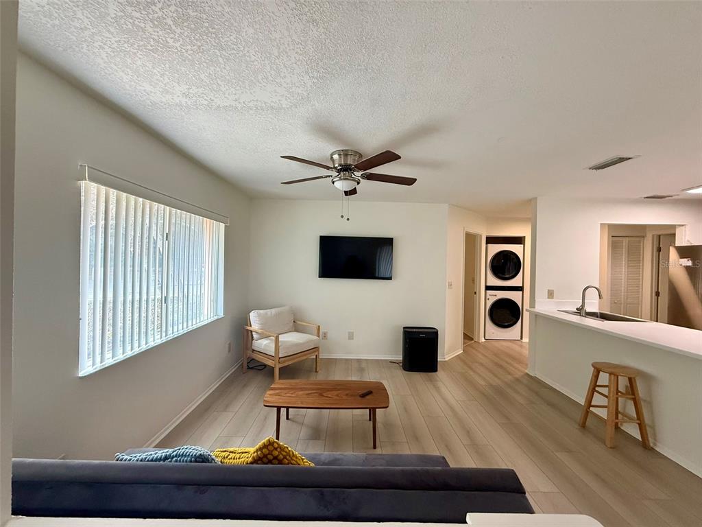 A living room with light wood floors, a ceiling fan, and a kitchen breakfast bar — 5202 WATERVIEW WAY UNIT 5202, WINTER HAVEN, FL