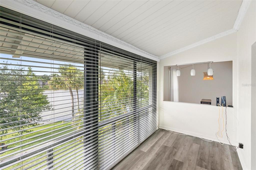 A sunroom with gray wood-look flooring, white walls, and large windows overlooking a lake — 200 MAITLAND AVENUE UNIT 174, ALTAMONTE SPRINGS, FL