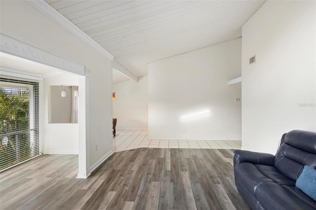 A living room with wood-look flooring, a vaulted ceiling, and a view into a tiled area — 200 MAITLAND AVENUE UNIT 174, ALTAMONTE SPRINGS, FL