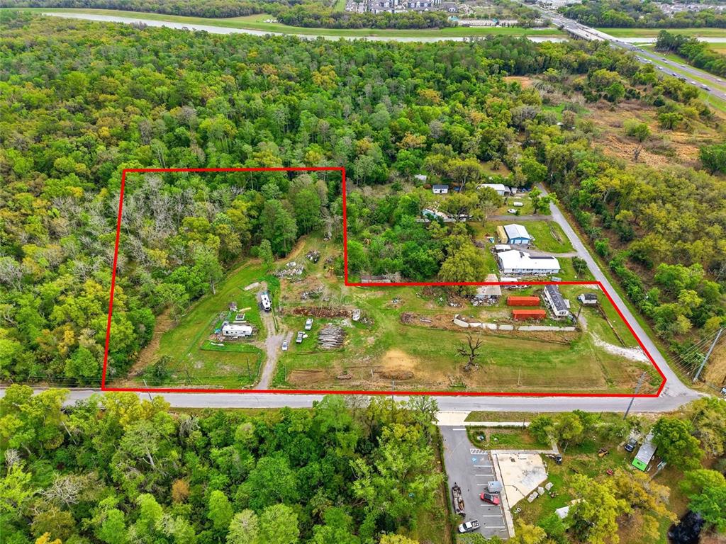 An aerial view shows a large, L-shaped plot of land outlined in red with structures — 9014 122ND AVENUE, TAMPA, FL