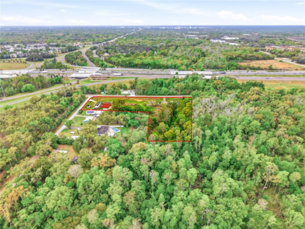 An aerial view shows a wooded lot with a red-outlined boundary near a highway — 9014 122ND AVENUE, TAMPA, FL