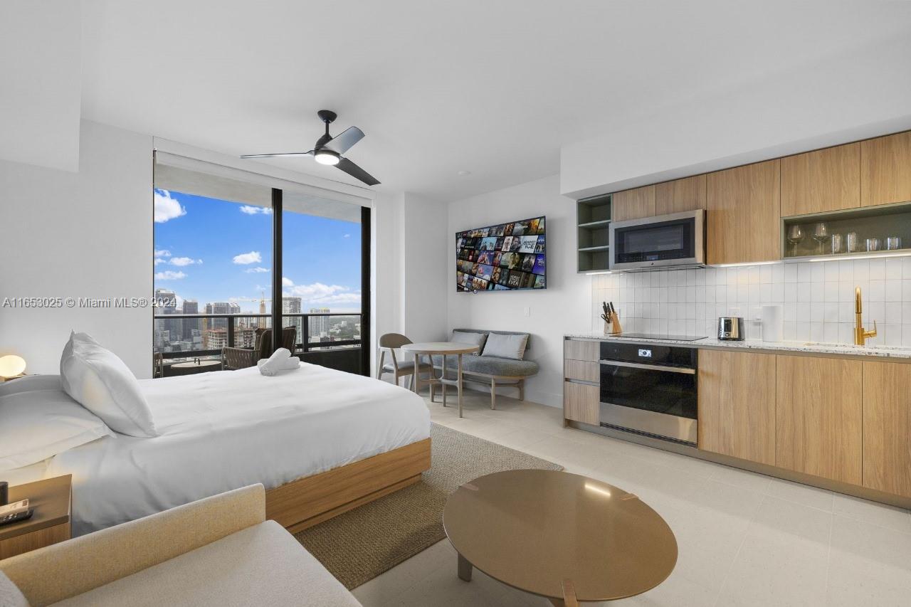 A studio apartment features a bed, kitchenette with wood cabinets, and a balcony with city views — 601 NE 1 # 4410, Miami FL 33132, MIAMI, FL