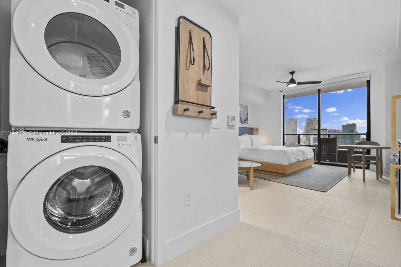 A stacked Whirlpool washer and dryer unit sits in a room overlooking a city skyline — 601 NE 1 # 4410, Miami FL 33132, MIAMI, FL