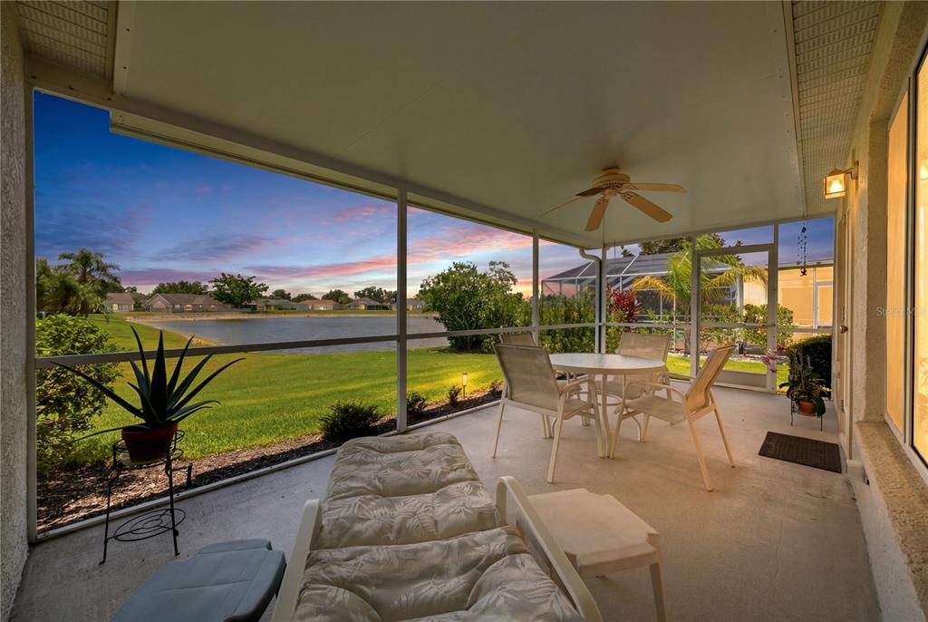 A screened-in patio with outdoor furniture overlooks a grassy lawn and a small lake — 4226 KINGSFIELD DRIVE, PARRISH, FL