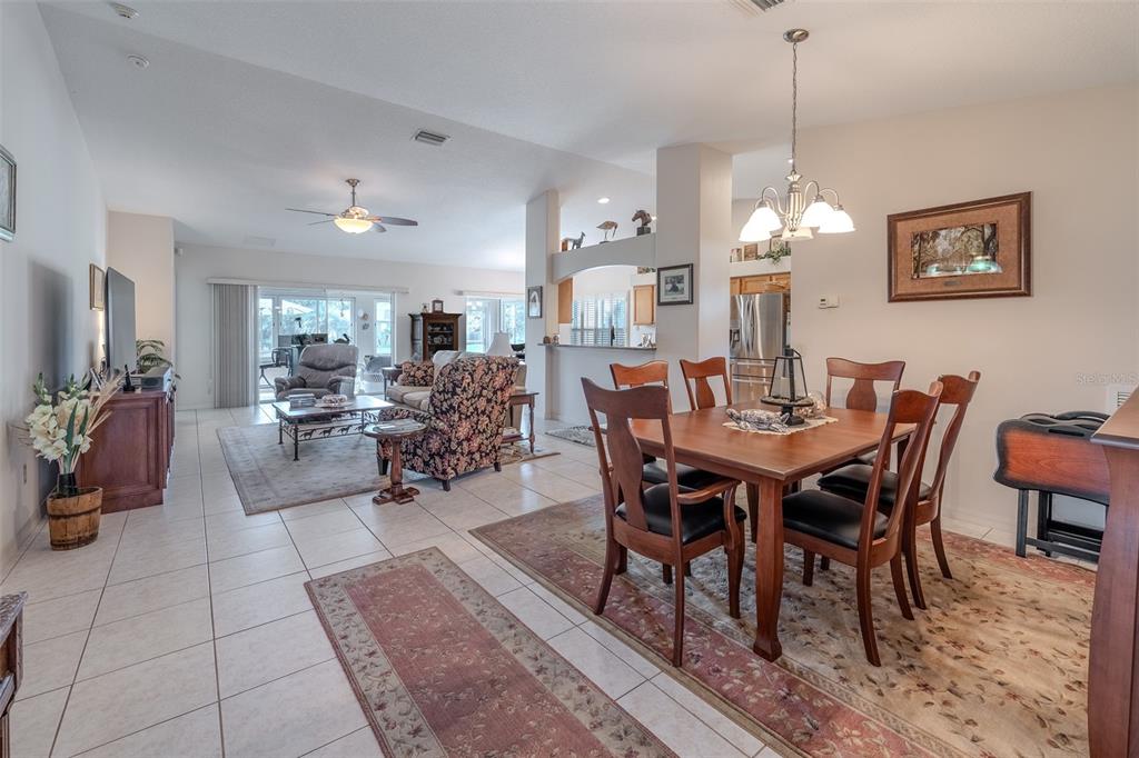 An open-concept dining area and living room feature tile floors, neutral walls, and traditional furniture — 15541 SW 11TH TERRACE ROAD, OCALA, FL